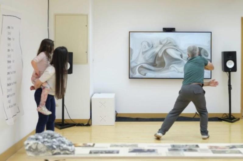 People dancing to a screen with music speakers and images around